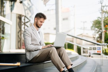 Yakışıklı, traşsız iş adamı. Şehir caddesinde dizüstü bilgisayarla, tabletle ve akıllı telefonla dolaşıyor.