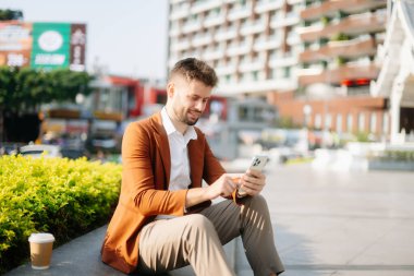 Yakışıklı, traşsız iş adamı. Şehir caddesinde dizüstü bilgisayarla, tabletle ve akıllı telefonla dolaşıyor.