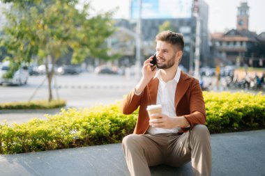 Başarılı iş adamı ofis yakınlarında çalışıyor. Güneş ışığında bir tablet ve akıllı telefon tutuyor.