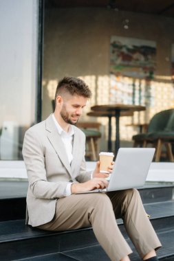 Başarılı iş adamı ofis yakınlarında çalışıyor. Güneş ışığında bir tablet ve akıllı telefon tutuyor.
