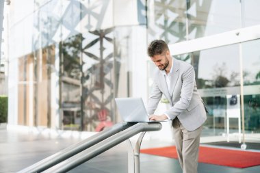 Başarılı iş adamı ofis yakınlarında çalışıyor. Güneş ışığında bir tablet ve akıllı telefon tutuyor.