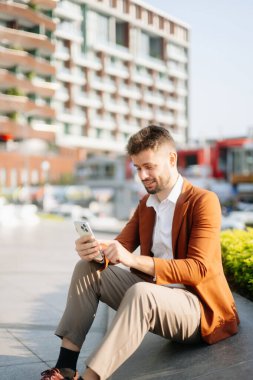 Yakışıklı, traşsız iş adamı. Şehir caddesinde dizüstü bilgisayarla, tabletle ve akıllı telefonla dolaşıyor.