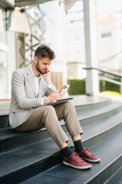 Yakışıklı, traşsız iş adamı. Şehir caddesinde dizüstü bilgisayarla, tabletle ve akıllı telefonla dolaşıyor.