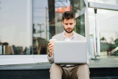 Yakışıklı, traşsız iş adamı. Şehir caddesinde dizüstü bilgisayarla, tabletle ve akıllı telefonla dolaşıyor.
