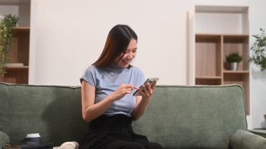 Evde cep telefonu kullanan Asyalı genç bir kadın.