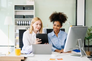 İş kadınları birlikte çalıştıkları ofiste dijital tablet ve dizüstü bilgisayarla toplantı yapıyorlar. 
