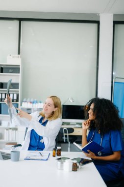 Doktor ve hemşire hastanın röntgenine bakıyor. Modern hastanede ekip çalışması yapıyorlar. Çeşitli Sağlık Hizmetleri Uzmanları Ekibi