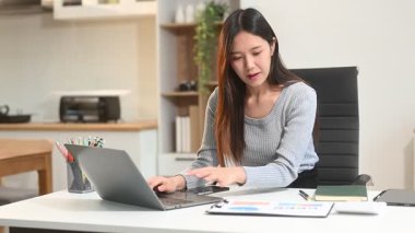 İş kadını ofis masasında dizüstü bilgisayar kullanıyor, vergi bildirimi yapıyor ve analitik araştırma yapıyor.