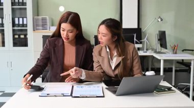 İş kadınları profesyonel tartışmalar yapıyorlar, belgelere bakıyorlar ve ofiste hesap makinesi ve dizüstü bilgisayar kullanıyorlar. İş takım çalışması başlangıç konsepti
