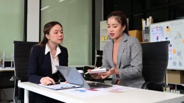 İş kadınları profesyonel tartışmalar yapıyorlar, belgelere bakıyorlar ve ofiste hesap makinesi ve dizüstü bilgisayar kullanıyorlar. İş takım çalışması başlangıç konsepti