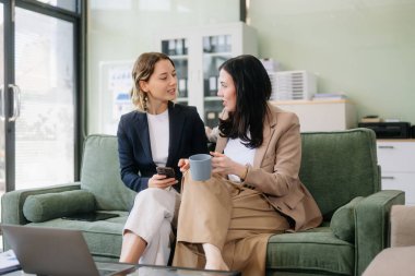 Profesyonel bir ofiste tabletle strateji kuran iki iş kadını. Bu modern işbirliği konseptiyle takım çalışmasını, liderliği ve yeniliği vurgula.