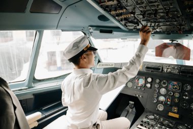 Asyalı özgüvenli erkek pilot kalkış ve uçuş planlarını kontrol ederken üniformalı.