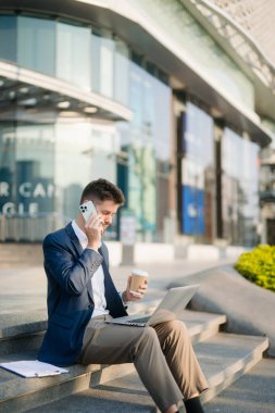 Modern iş adamı açık havada, tablet kullanıyor. İş, teknoloji ve yenilik temaları için idealdir. Kurumsal, profesyonel ve şehir yaşam tarzı kavramı