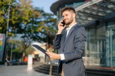 Modern iş adamı açık havada, tablet kullanıyor. İş, teknoloji ve yenilik temaları için idealdir. Kurumsal, profesyonel ve şehir yaşam tarzı kavramı