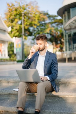 Modern iş adamı açık havada, tablet kullanıyor. İş, teknoloji ve yenilik temaları için idealdir. Kurumsal, profesyonel ve şehir yaşam tarzı kavramı