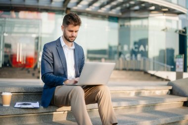 Modern iş adamı açık havada, tablet kullanıyor. İş, teknoloji ve yenilik temaları için idealdir. Kurumsal, profesyonel ve şehir yaşam tarzı kavramı