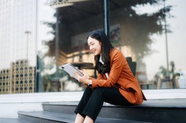 Ofis dışında tablet kullanan kendine güvenen Asyalı kadın. iş merkezi arkaplanı