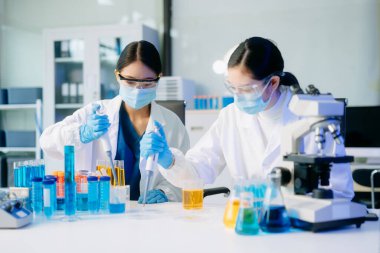 Tıp laboratuarında mikroskop kullanarak araştırma yapan genç bilim adamları.  