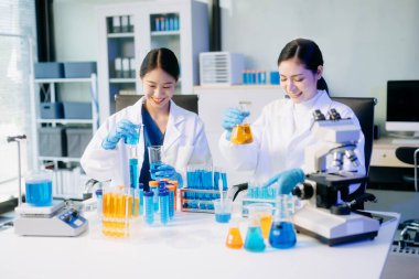 Tıp laboratuarında mikroskop kullanarak araştırma yapan genç bilim adamları.  