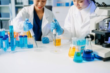 Tıp laboratuarında mikroskop kullanarak araştırma yapan genç bilim adamları.  