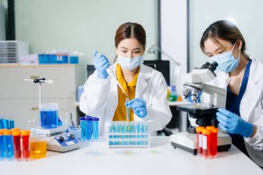 Laboratuar önlüklü bilim adamları, cam eşyalar üzerinde araştırma yapıyorlar ve modern, yüksek teknoloji laboratuvarında kimyasallarla çalışıyorlar..