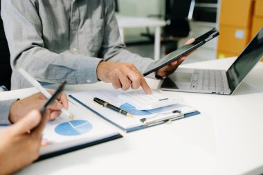 Akıllı telefon ve hesap makinesi olan ofis masasındaki iş belgeleri dijital tablet ve sosyal ağ diyagramı olan grafik işleri ve büroda çalışan verileri tartışan iki meslektaş