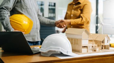 İnşaat ekibi, inşaat projeleriyle ilgili danışmanlık yapmak için ofis merkezindeki sarı miğferin arkasında yeni proje planını başlatın..