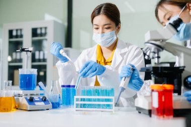 Laboratuar önlüklü bilim adamları, cam eşyalar üzerinde araştırma yapıyorlar ve modern, yüksek teknoloji laboratuvarında kimyasallarla çalışıyorlar..