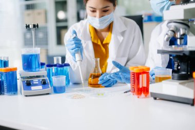 Laboratuar önlüklü bilim adamları, cam eşyalar üzerinde araştırma yapıyorlar ve modern, yüksek teknoloji laboratuvarında kimyasallarla çalışıyorlar..