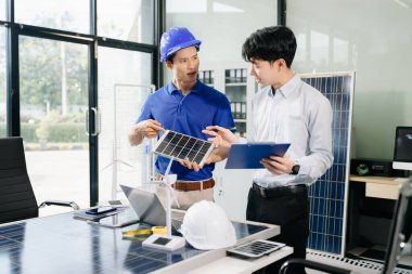 İki Asyalı mühendis, dizüstü bilgisayar kullanarak, modern ofis ortamında yenilik ve sürdürülebilirliği tartışan bir güneş enerjisi ve rüzgar enerjisi projesinde işbirliği yapıyorlar. Temiz enerji, takım çalışması ve ilerleme