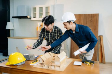 Mimarlar ve mühendisler bir mimari ofiste dizüstü bilgisayar kullanarak bir yapı modeli tasarlayarak, planlayarak ve yaratıcılıkla işbirliği yaparlar. 