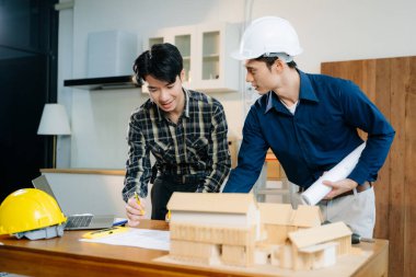 Mimarlar ve mühendisler bir mimari ofiste dizüstü bilgisayar kullanarak bir yapı modeli tasarlayarak, planlayarak ve yaratıcılıkla işbirliği yaparlar. 