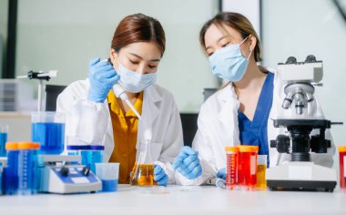 Laboratuar önlüklü bilim adamları, cam eşyalar üzerinde araştırma yapıyorlar ve modern, yüksek teknoloji laboratuvarında kimyasallarla çalışıyorlar..