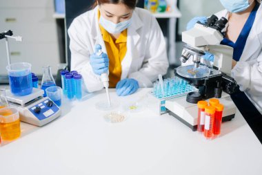 Laboratuar önlüklü bilim adamları, cam eşyalar üzerinde araştırma yapıyorlar ve modern, yüksek teknoloji laboratuvarında kimyasallarla çalışıyorlar..