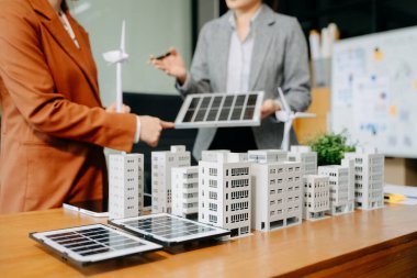 Muhtelif etnik çeşitlilikte iş adamlarından oluşan bir ekip, konut projesinden elde edilen yapı modeline bakıyor. Yeşil iş şirketi ve Güneş Enerjisi Çevre Kenti Kavramı