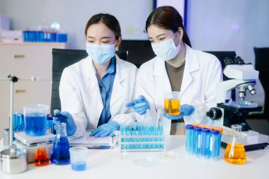 Tıp laboratuarında mikroskop kullanarak araştırma yapan genç bilim adamları.  