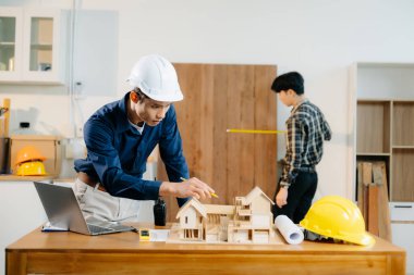 Mimarlar ve mühendisler bir mimari ofiste dizüstü bilgisayar kullanarak bir yapı modeli tasarlayarak, planlayarak ve yaratıcılıkla işbirliği yaparlar. 