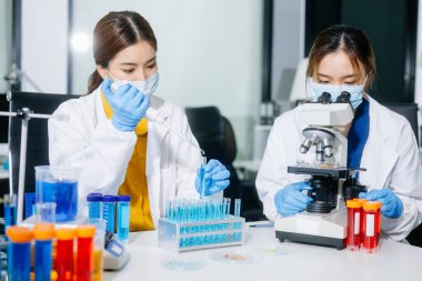 Laboratuar önlüklü bilim adamları, cam eşyalar üzerinde araştırma yapıyorlar ve modern, yüksek teknoloji laboratuvarında kimyasallarla çalışıyorlar..