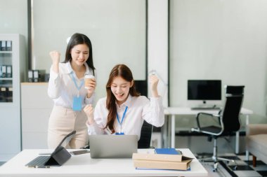 Asyalı mutlu iş kadınları dizüstü bilgisayar ve tablet kullanıyorlar. Takım çalışması, finansal pazarlama ekibi, modern ofis odasında otururken. 