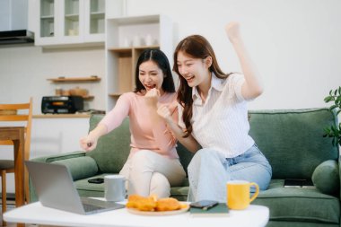 İki mutlu kadın rahat bir oturma odasında dizüstü bilgisayar kullanarak uzaktan çalışmaktan zevk alır. Serbest, modern yaşam tarzının mükemmel bir karışımı. 