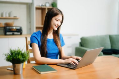 Parlak bir mutfakta kulaklıklı mutlu bir kadın tablet üzerinde çalışıyor. Uzaktan çalışma, serbest çalışma, evdeki modern yaşam tarzı temaları için ideal