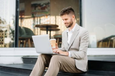 Başarılı iş adamı ofis yakınlarında çalışıyor. Güneş ışığında bir tablet ve akıllı telefon tutuyor.