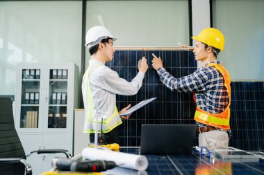 İki Asyalı mühendis, dizüstü bilgisayar kullanarak, modern ofis ortamında yenilik ve sürdürülebilirliği tartışan bir güneş enerjisi ve rüzgar enerjisi projesinde işbirliği yapıyorlar. Temiz enerji, takım çalışması ve ilerleme