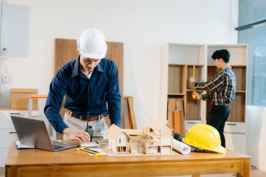 Mimarlar ve mühendisler bir mimari ofiste dizüstü bilgisayar kullanarak bir yapı modeli tasarlayarak, planlayarak ve yaratıcılıkla işbirliği yaparlar. 