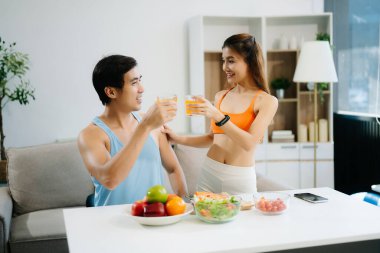 Fitness çifti taze salata, meyve suyu ve meyve suyuyla sağlıklı bir yaşam sürerler. Sağlığın, beslenmenin ve aktif yaşam tarzının mükemmel dengesi.