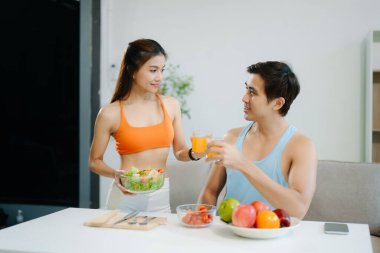 Fitness çifti taze salata, meyve suyu ve meyve suyuyla sağlıklı bir yaşam sürerler. Sağlığın, beslenmenin ve aktif yaşam tarzının mükemmel dengesi.