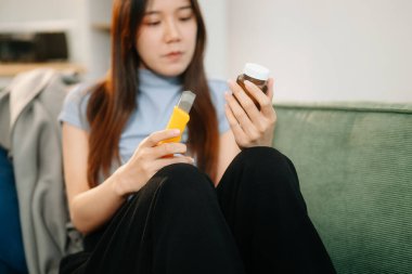 Kanepede çok sayıda hapla oturan genç Asyalı kadın depresyondaki kadın aşırı doz ve depresyon konseptiyle kendini öldürmek istiyor.