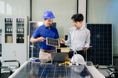 İki Asyalı mühendis, dizüstü bilgisayar kullanarak, modern ofis ortamında yenilik ve sürdürülebilirliği tartışan bir güneş enerjisi ve rüzgar enerjisi projesinde işbirliği yapıyorlar. Temiz enerji, takım çalışması ve ilerleme