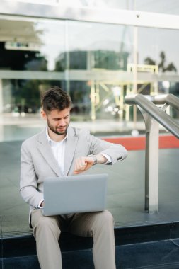 Başarılı iş adamı ofis yakınlarında çalışıyor. Güneş ışığında bir tablet ve akıllı telefon tutuyor.