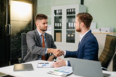 İki ofis arkadaşı, modern bir çalışma alanında yeni bir proje için fikir alışverişinde bulunuyor.                          